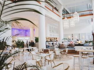 a restaurant with white tables and chairs and people at Pullman Cairns International in Cairns