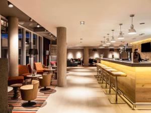 a hotel lobby with a bar and tables and chairs at ibis Edinburgh Centre South Bridge – Royal Mile in Edinburgh