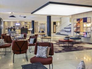 a lobby with chairs and tables and a staircase at Hotel Mercure Blois Centre in Blois
