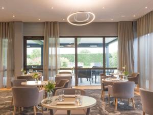 a restaurant with tables and chairs and a large window at Pullman Toulouse in Blagnac