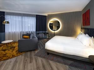 a hotel room with a large bed and a chair at Mercure Antwerp City South in Antwerp