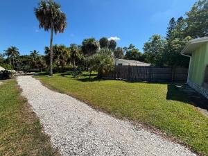 a gravel driveway with a palm tree in a yard at Seahorse - Tiny Home 1.2 Mi, 2 Beach Kitchen W & D Queen Bed in Bonita Springs