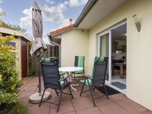 a patio with a table and chairs and an umbrella at Stranddistel links mit Sauna in Boiensdorf