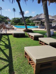a group of benches in the grass near a pool at Eco Paradise 213 in Cumbuco