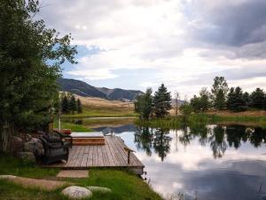 a dock on a lake with a boat in it at 104-Acre Private Ranch Retreat in Paradise Valley Montana in White City