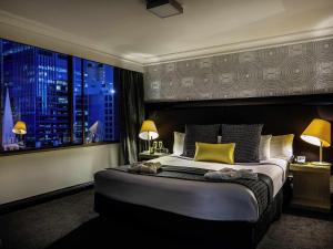 une chambre avec un grand lit avec une grande fenêtre dans l'établissement Pullman Brisbane King George Square, à Brisbane