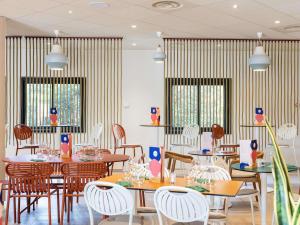 a restaurant with tables and chairs and windows at ibis Beziers Est Mediterranee A9/A75 in Béziers