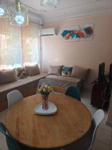 - un salon avec une table en bois et un vase de fleurs dans l'établissement Baraka house, à Sidi Yahia az Zaʼer