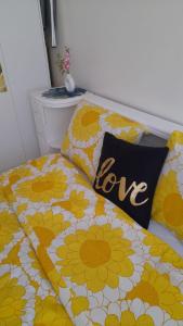 un lit avec des fleurs jaunes et blanches avec un coussin d'amour dans l'établissement Baraka house, à Sidi Yahia az Zaʼer