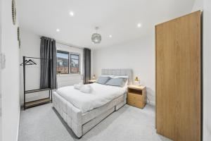 a bedroom with a large white bed and a window at Lara's 4 Bedroom House near Coventry in Coventry