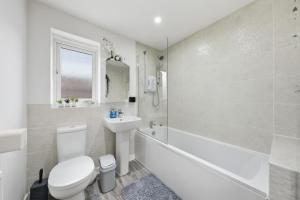 a white bathroom with a toilet and a tub and a sink at Lara's 4 Bedroom House near Coventry in Coventry +71 photos