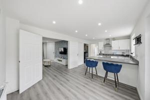 a kitchen with white cabinets and blue bar stools at Lara's 4 Bedroom House near Coventry in Coventry