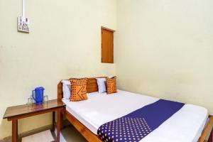 a small room with a bed and a wooden table at Hotel O Shivaye Rest House in Deoghar