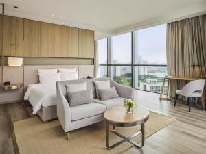 Una habitación de hotel con una cama, un sofá y una mesa. en Novotel Shanghai Qingpu Excellence, en Shanghái