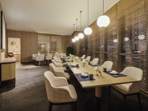 un comedor con una mesa larga y sillas blancas en Novotel Shanghai Qingpu Excellence, en Shanghái