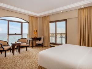 a hotel room with a bed and a desk and windows at Pullman Resort Al Marjan Island in Ras al Khaimah