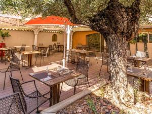 an outdoor patio with tables and chairs and a tree at Novotel Narbonne Sud A9/A61 in Narbonne