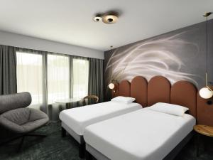 a hotel room with two beds and a chair at Mercure Debrecen in Debrecen