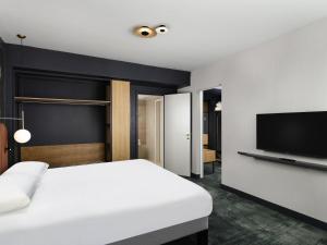 a bedroom with a white bed and a flat screen tv at Mercure Debrecen in Debrecen +126 photos