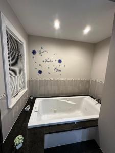 baño con bañera con flores en la pared en Spacious 3 Bedroom Near Train Station, en Malden 6 fotos más