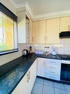 a kitchen with white cabinets and black counter tops at The Cosy Retreat Guest House in Gaborone