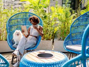 a woman sitting on a chair with a white dog at Novotel SP Jardins in Sao Paulo