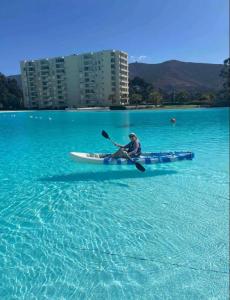 a person in a kayak in the blue water at Departamento Papudo laguna in Quinquimo