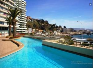 a swimming pool with blue water in front of a building at Reñaca Cochoa departamento frente al mar in Vina del Mar