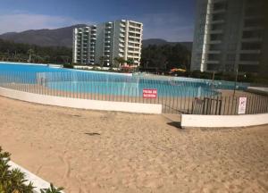 QuinquimoにあるDepartamento Papudo lagunaの大きなスイミングプール(建物のあるビーチの隣)