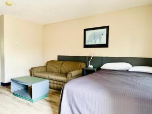 a bedroom with a bed and a couch at Plains Motor Inn in Stettler