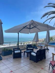 a patio with chairs and an umbrella and the ocean at Reñaca Cochoa departamento frente al mar in Vina del Mar +7 photos