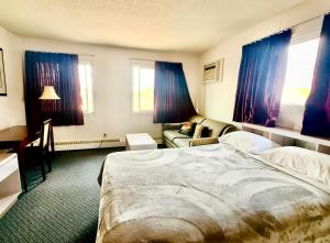 a bedroom with a bed and a couch and windows at Plains Motor Inn in Stettler