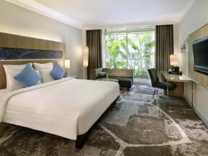 a hotel room with a large bed and a television at Novotel Jakarta Mangga Dua Square in Jakarta