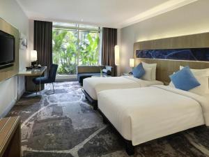 a hotel room with two beds and a television at Novotel Jakarta Mangga Dua Square in Jakarta +64 photos