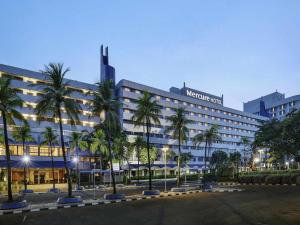 a large building with palm trees in front of it at Mercure Convention Center Ancol in Jakarta