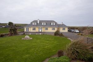 a large yellow house with a lawn in front of it at Atlantic View B&B in Liscannor