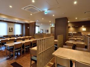 Un comedor con mesas y sillas de madera. en Hotel Route Inn Kanonji, 