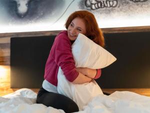 a woman sitting on a bed hugging a pillow at ibis Styles Hamburg Barmbek in Hamburg +92 photos