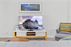 Una sala de estar con un televisor en una pared blanca. en Little Rocky Retreat, en Perisher Valley