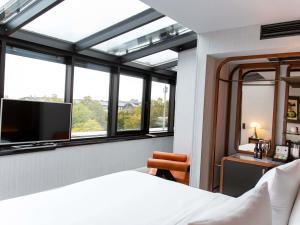 a bedroom with a bed and a tv and windows at MUZE Hotel Dusseldorf - Handwritten Collection in Düsseldorf