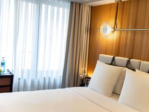a bedroom with a bed with white pillows and a window at MUZE Hotel Dusseldorf - Handwritten Collection in Düsseldorf