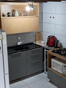 a small kitchen with a sink and a microwave at Chalé aconchegante à 300mts do mar in Arroio do Silva