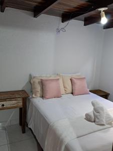 a bedroom with a bed with pink and white pillows at Chalé aconchegante à 300mts do mar in Arroio do Silva