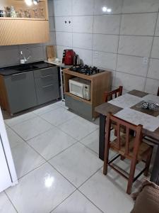 a kitchen with a table and a stove top oven at Chalé aconchegante à 300mts do mar in Arroio do Silva +5 photos