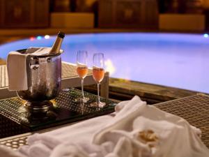 two glasses of wine on a table next to a swimming pool at Grand Mercure Imperial Palace Seoul Gangnam in Seoul