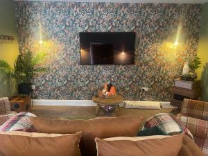 a living room with a couch and a tv on a wall at The Coachmans Cottage in Rock Ferry