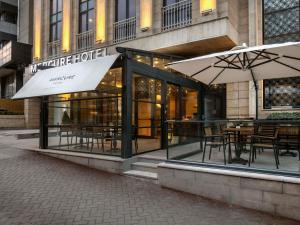 a restaurant with tables and umbrellas in front of a building at Mercure Ankara Kızılay in Ankara