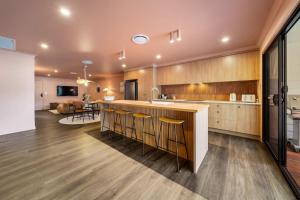 a kitchen with wooden cabinets and a bar with stools at Estelles Place by Discover Stradbroke in Amity Point