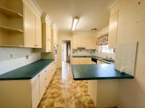 a large kitchen with white cabinets and green counter tops at Creswell Street Cottage in West Wyalong