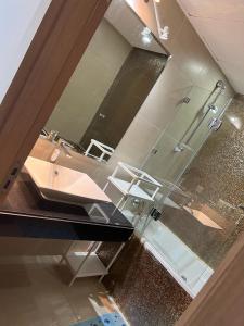 a bathroom with a sink and a shower with a mirror at Luxurious Seaside Apartment in Sidi Bouqnadel